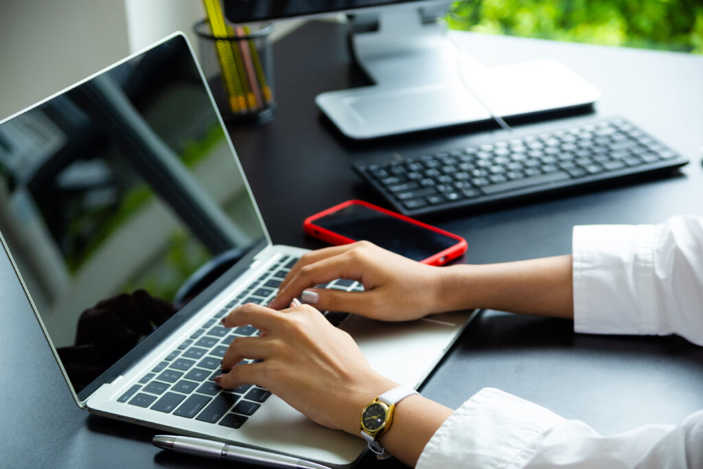 Woman typing on laptop at desk.